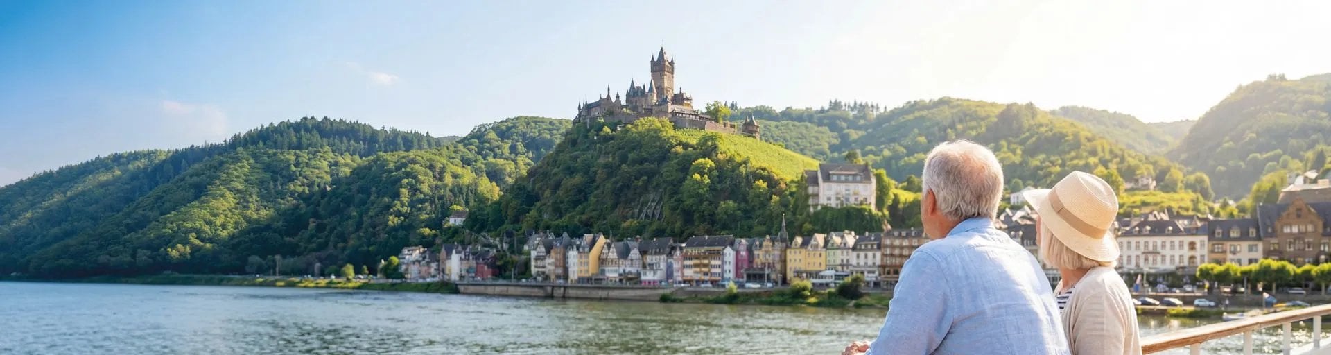 Couple regardant château médiéval sur colline boisée surplombant rivière et ville historique