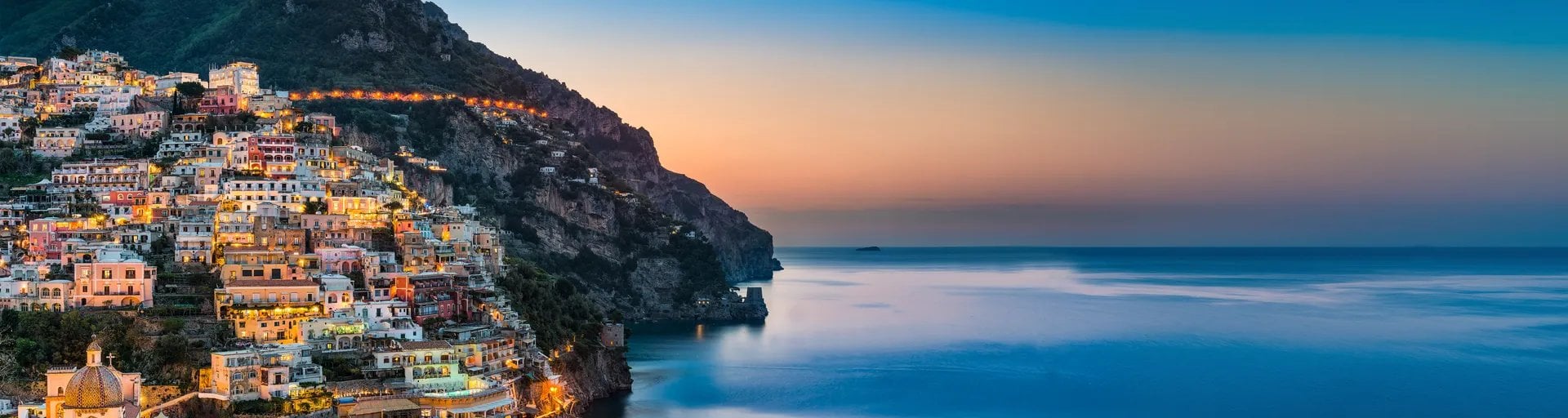 Village côtier coloré construire sur falaise rocheuse avec mer bleue au coucher du soleil